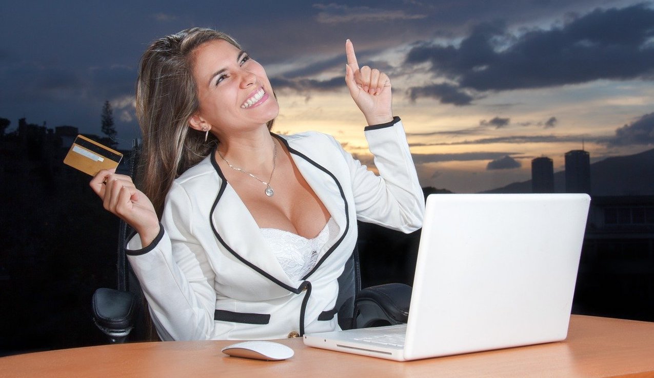 Woman holding a credit card while pointing upwards