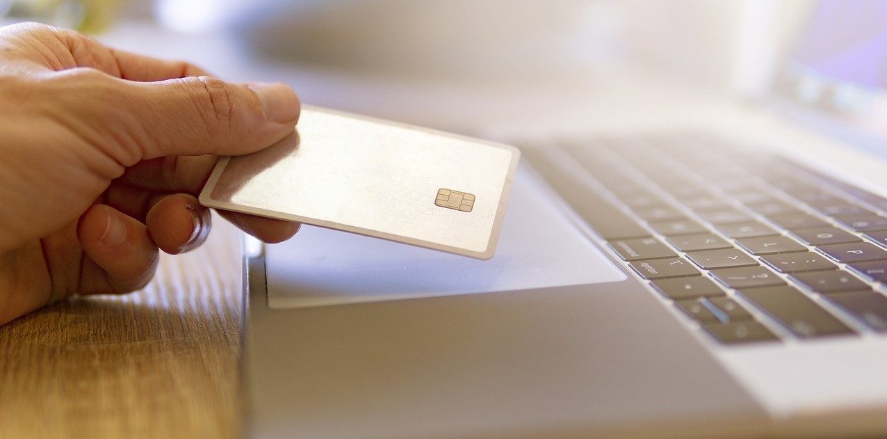 Person holding a credit card in front of a laptop