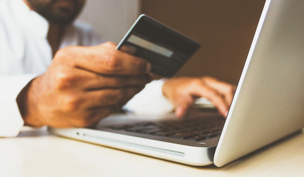 Man looking at his credit card while using his laptop