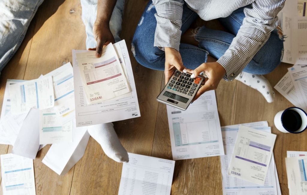 Couple using a calculator to compute their bills on the floor