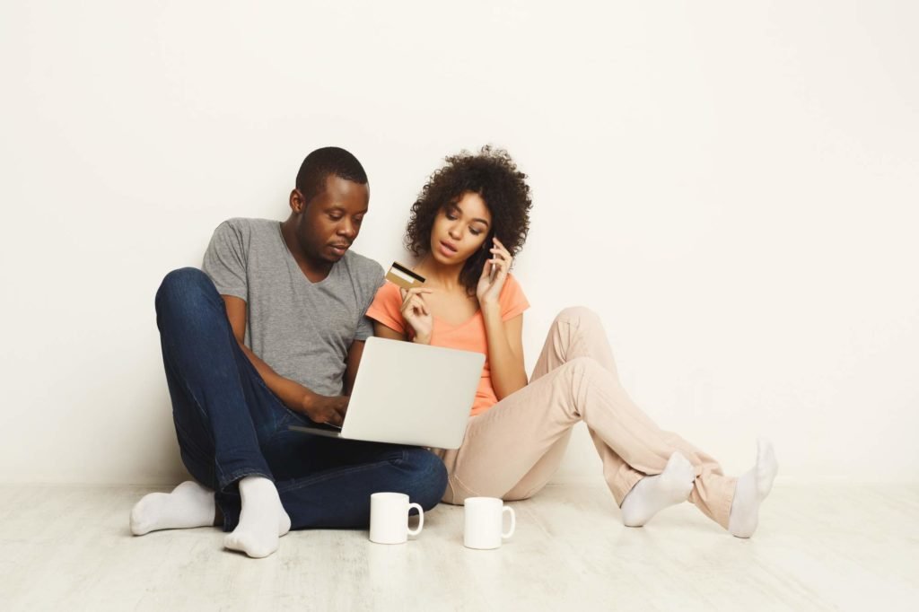 Couple looking at a laptop while holding out a credit card