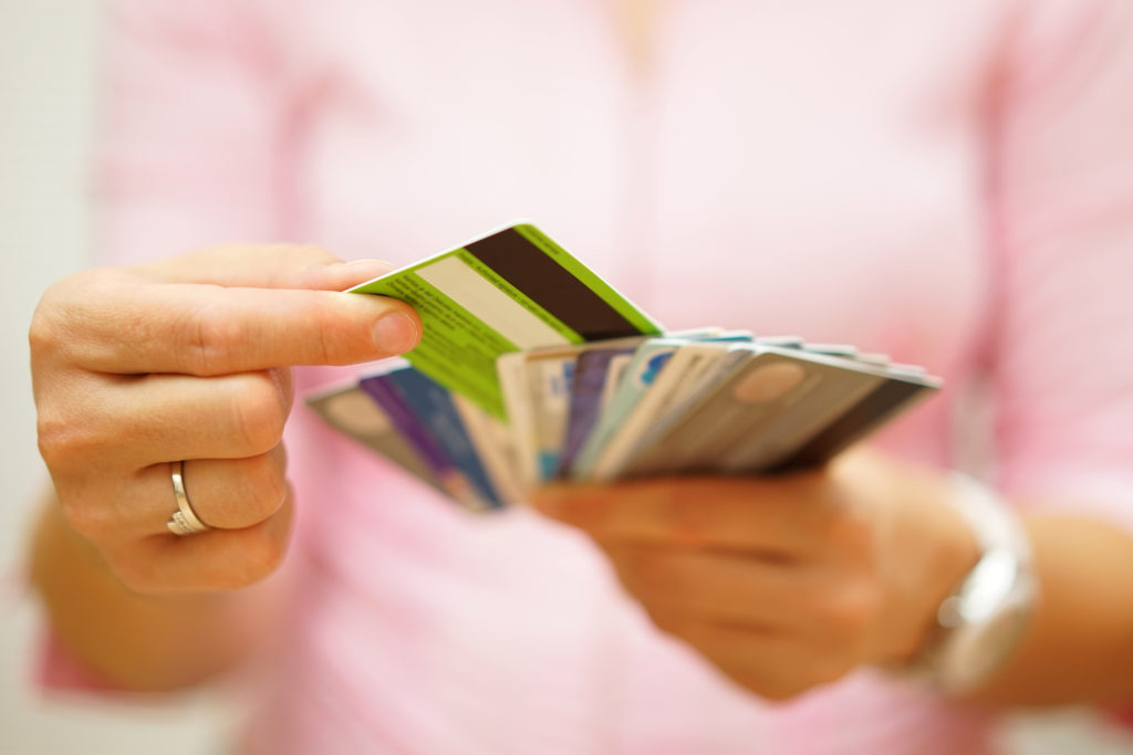 Person choosing a credit card from the different credit cards she's holding with her hands