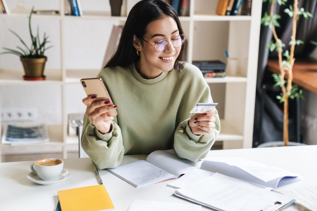 Woman holding a credit card on one hand, while holding a smartphone on the other