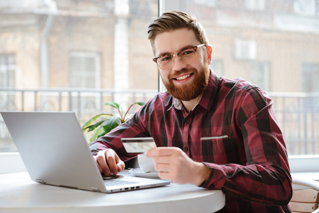 Man holding a credit card while using a laptop