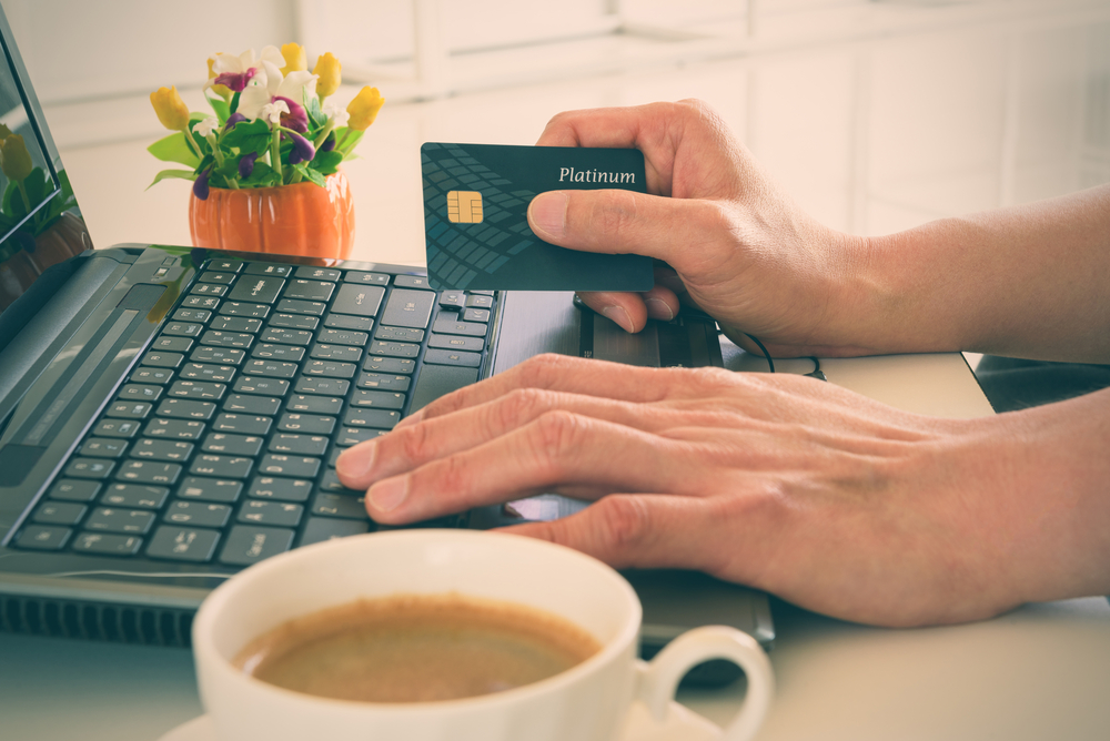 Person holding a credit card while using a laptop