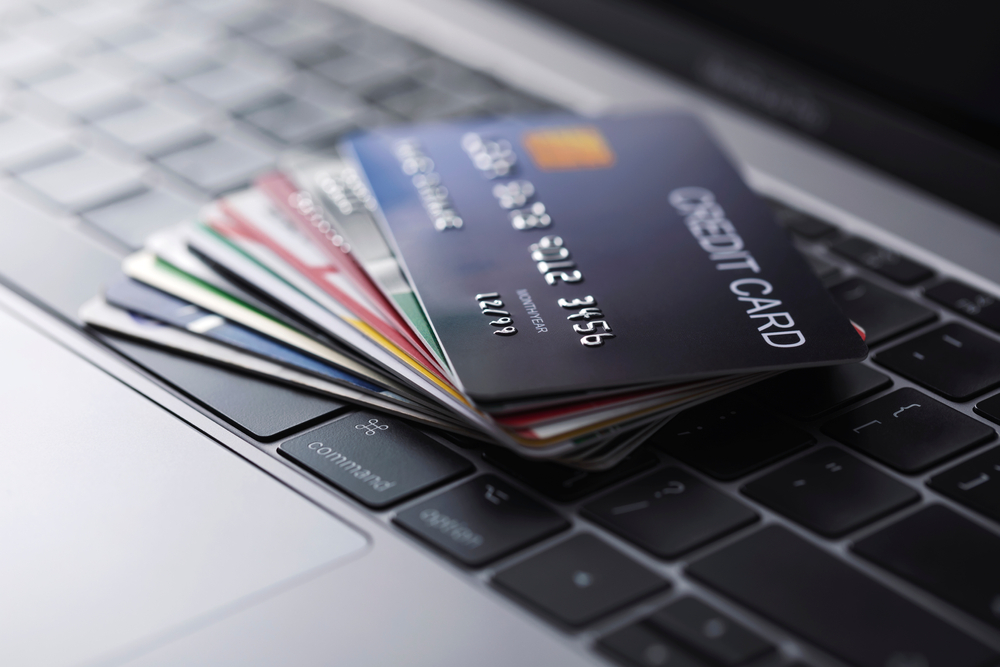 Several credit cards stacked in a pile on top of a laptop