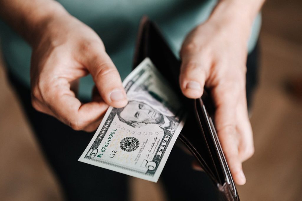 Man taking out a 5 dollar bill from his wallet