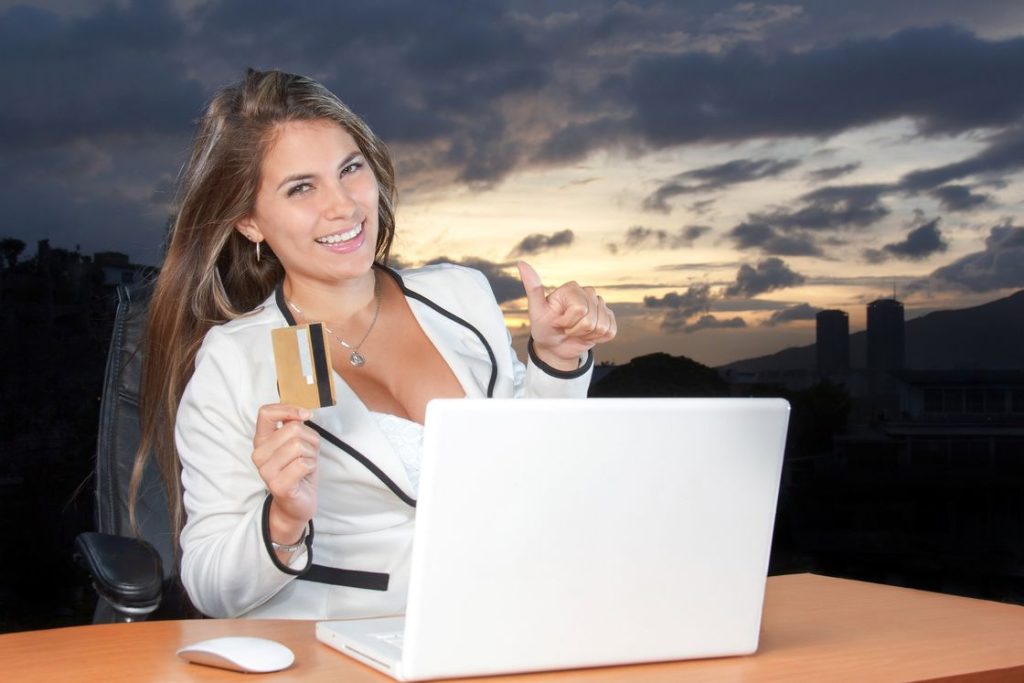 Woman holding a credit card while using a laptop on her table