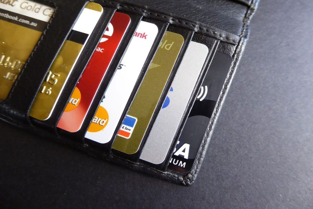 Different kinds of credit cards placed on the card holder section of a long black wallet