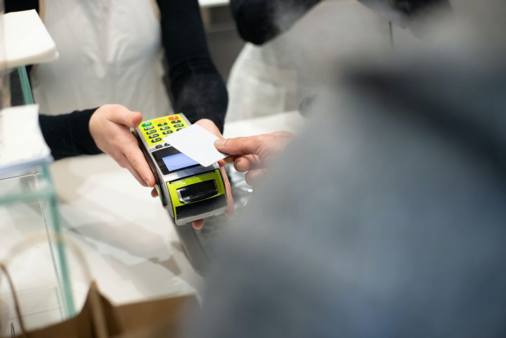 Woman holding a portable card reader to help the customer with his payment via credit card