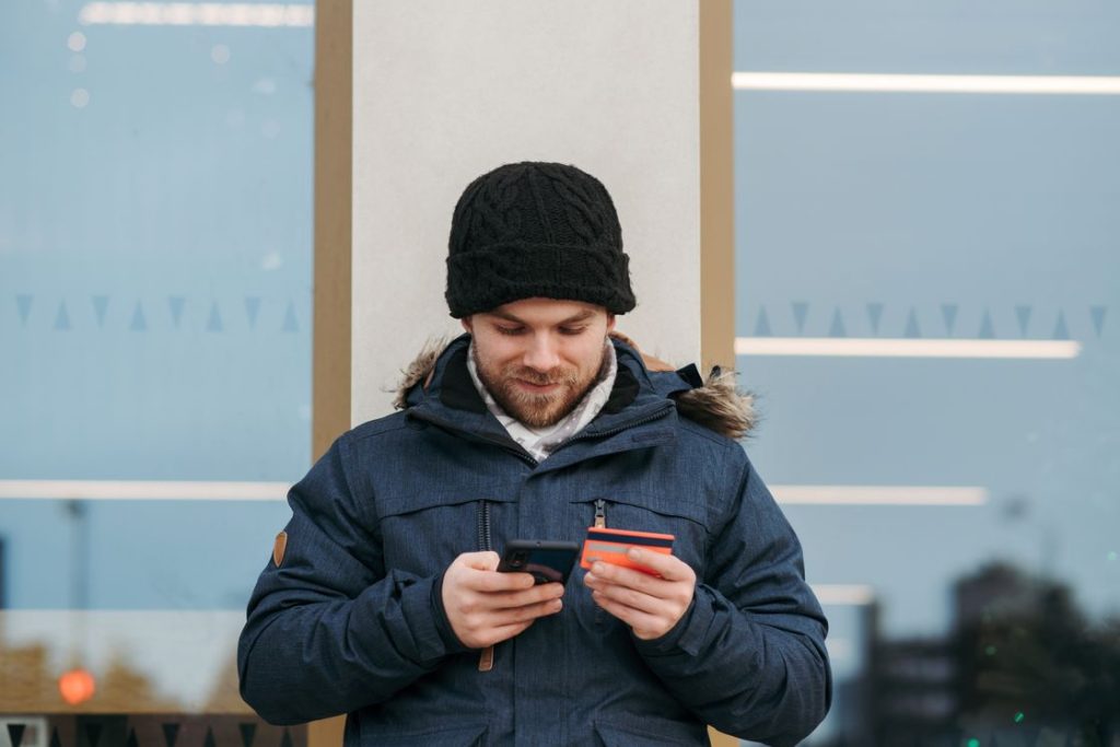 Man using his phone while holding his credit card