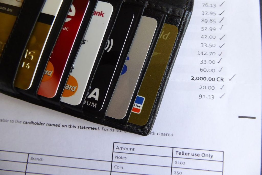 Different kinds of credit cards inserted into a wallet while it rests on top of a credit card statement