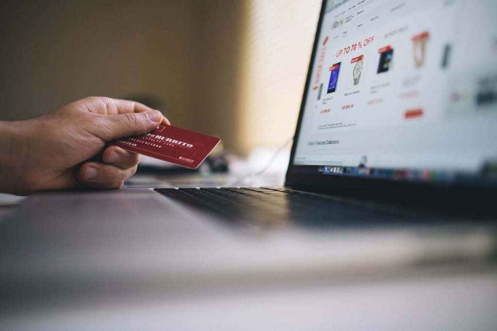 Person holding a red credit card while browsing a shopping cart