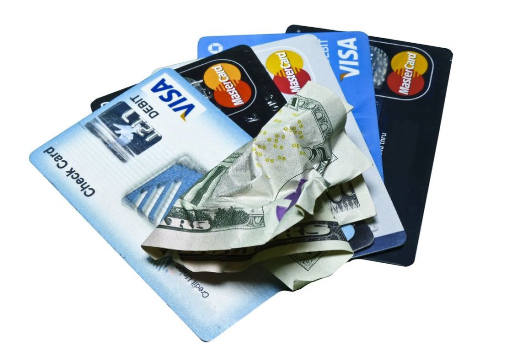 Four types of credit cards laid out in a table with a crumpled dollar bill at the center