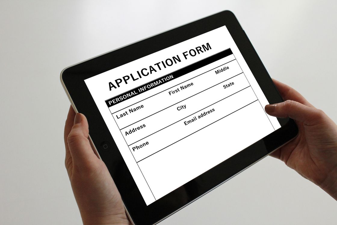 Person holding a tablet with an online application form