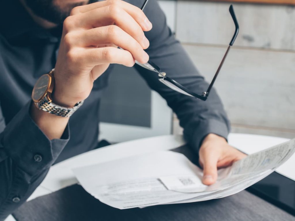 Man holding his glasses while looking at printed documents