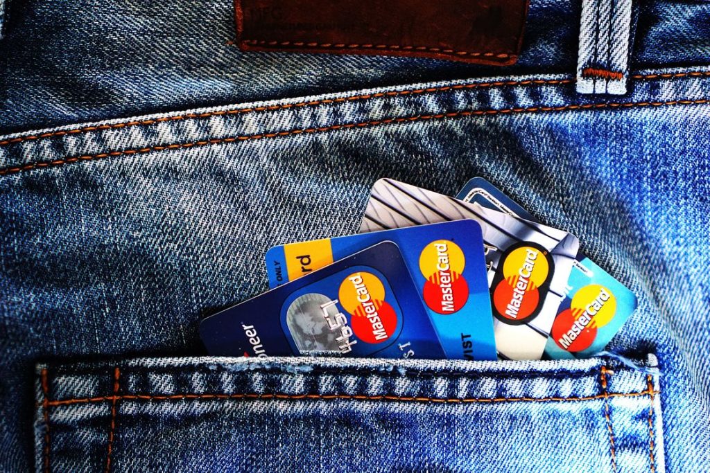 Various credit cards peeking on the edge of a denim pocket