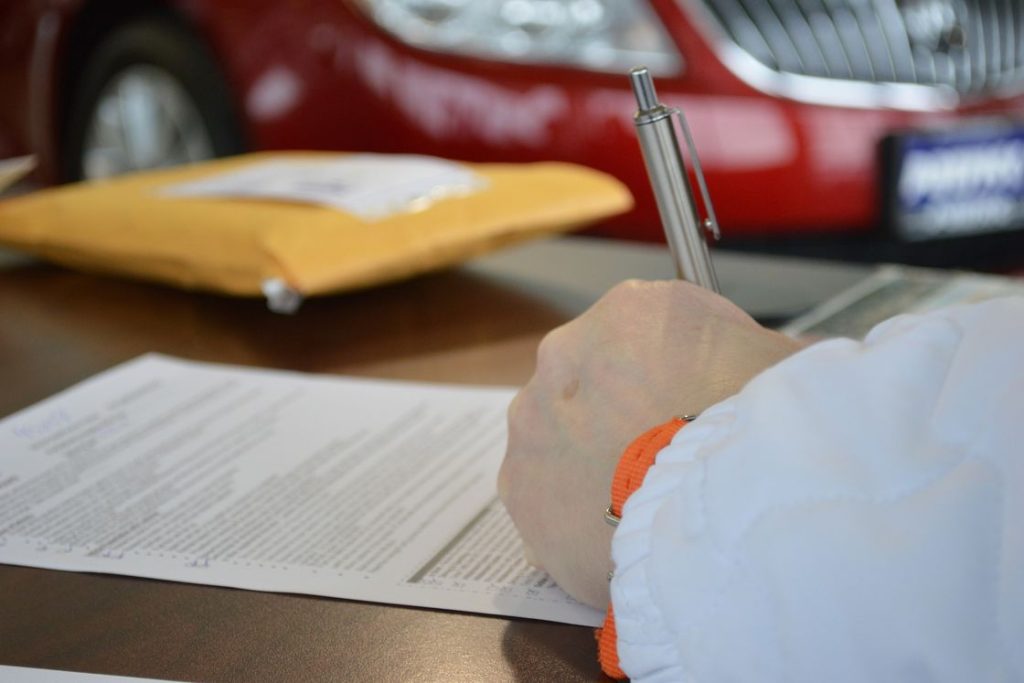 Person signing a document with a pen