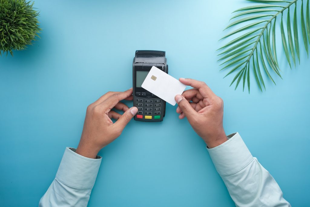 A credit card and a terminal payment in a tropical vibe background