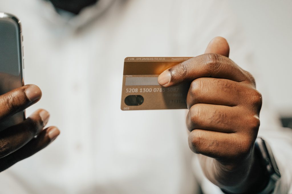 A man holding his credit card on his left hand and her phone on his right hand