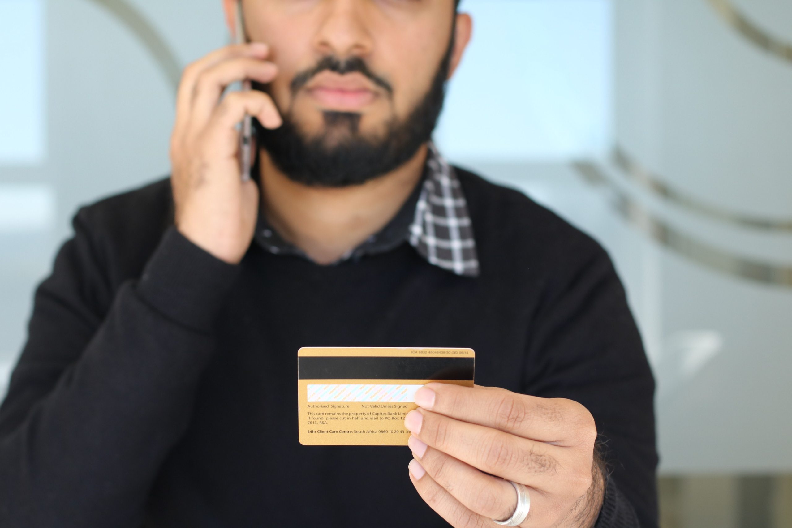 A man calling someone on the phone while holding his credit card