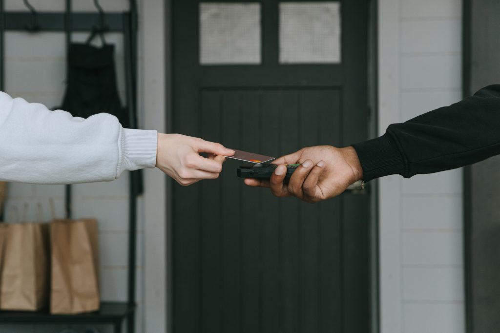 A man holding a credit card swiping it on the terminal payment that the other man is holding