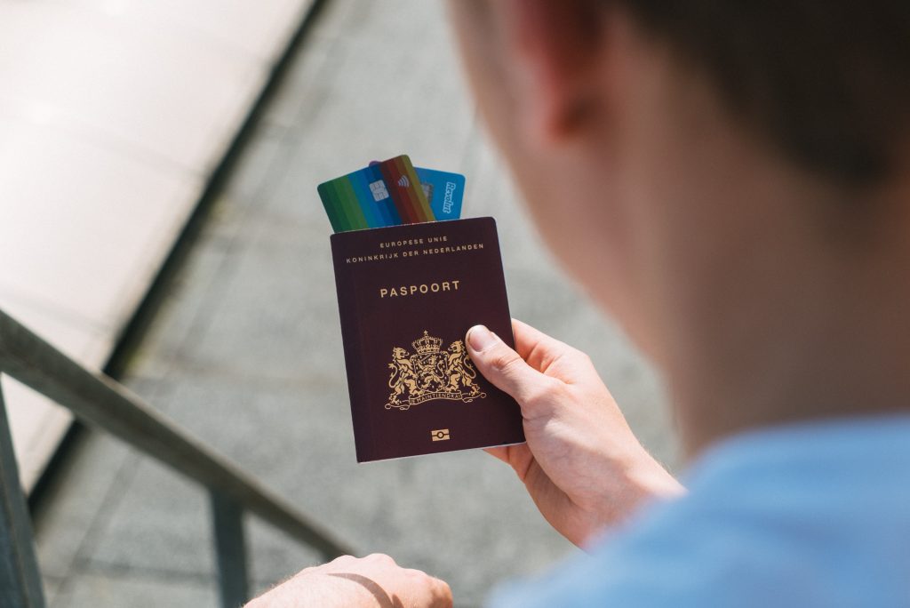 A man holding a passport with a credit card inside it
