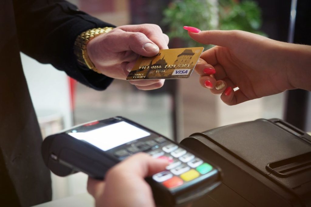 Person handing out his credit card to a woman holding a payment terminal