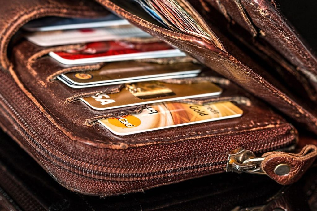 Various kinds of credit cards are placed on the card holders of a long brown wallet