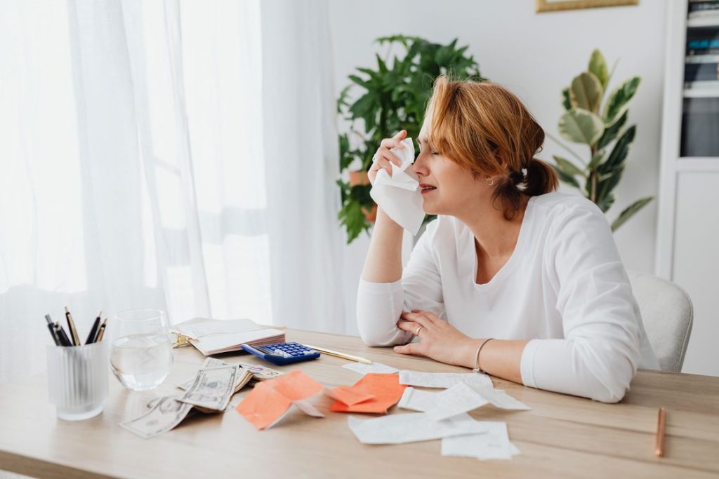 Woman holding a piece of tissue while lamenting her financial situation