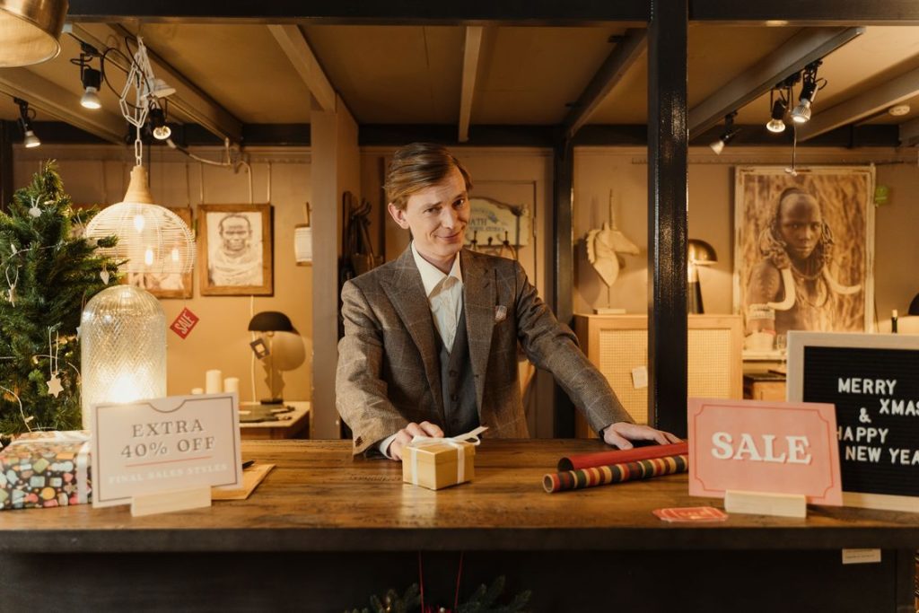 Man standing at the counter of a store after wrapping a customer's purchase in a gift box