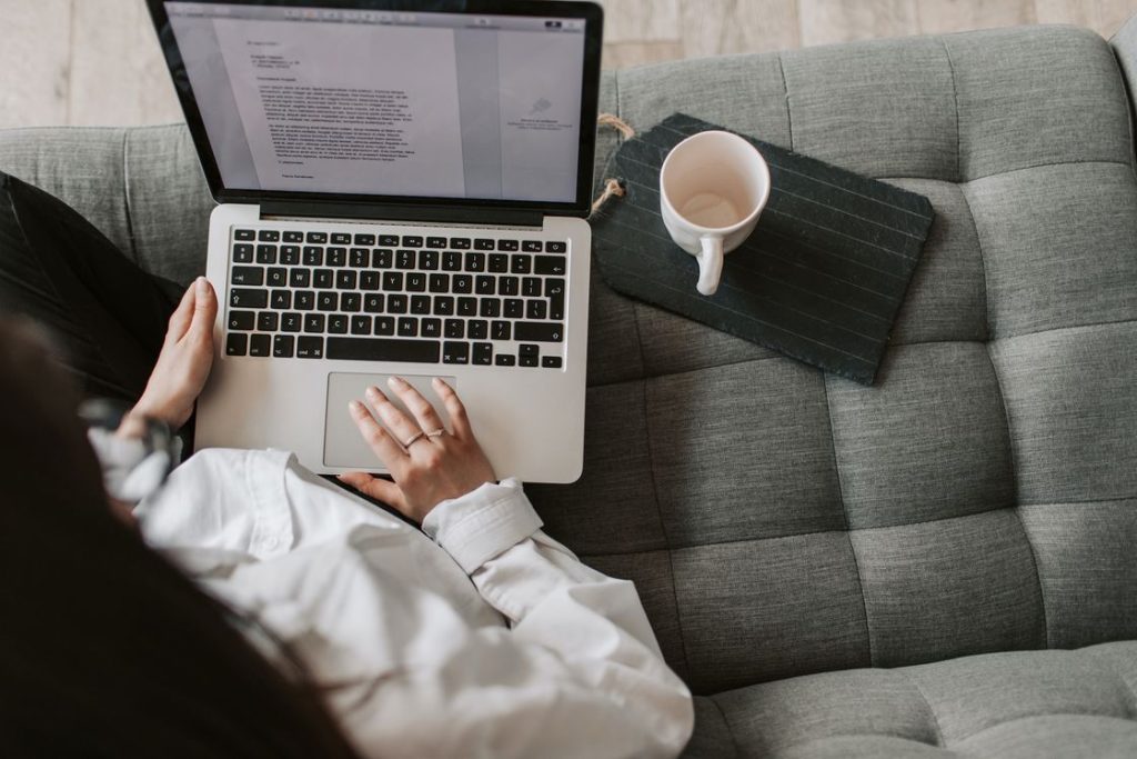 Woman using her laptop while sitting on her gray couch