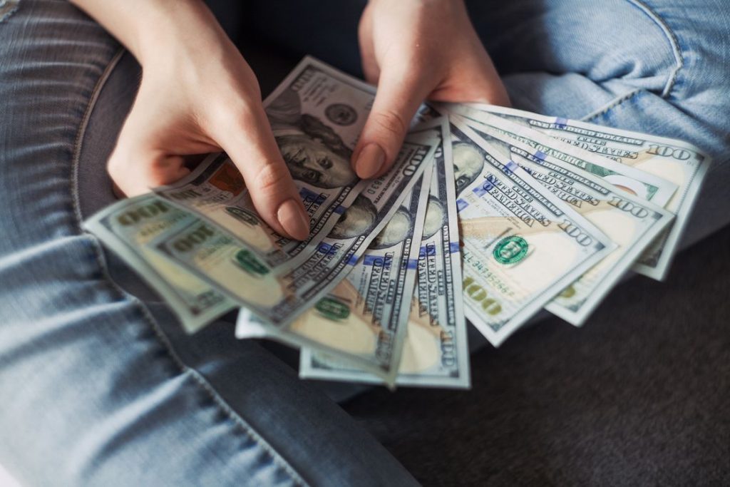 Person holding spread out dollar bills with two hands