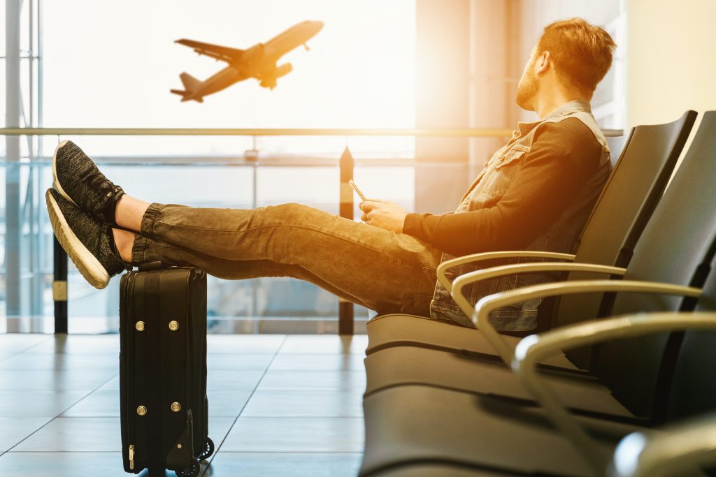 A man sitting on the airport while watching an airplane take off