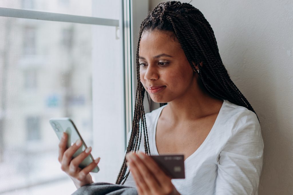A woman holding a credit card while looking at her phone
