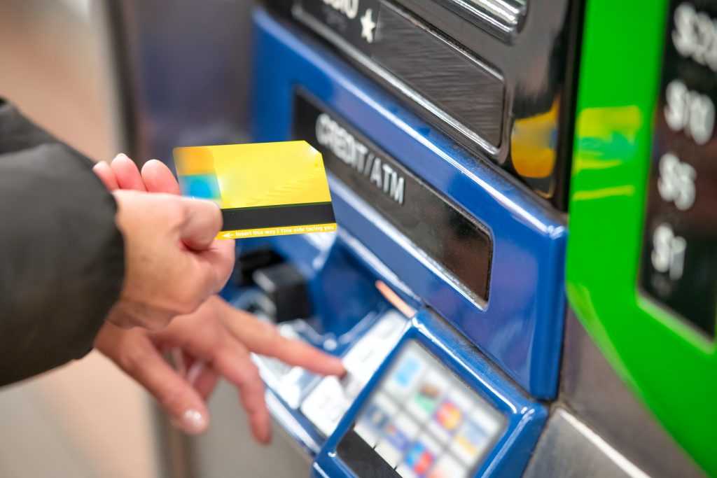 A person holding a credit card and pressing keys on the ATM machine