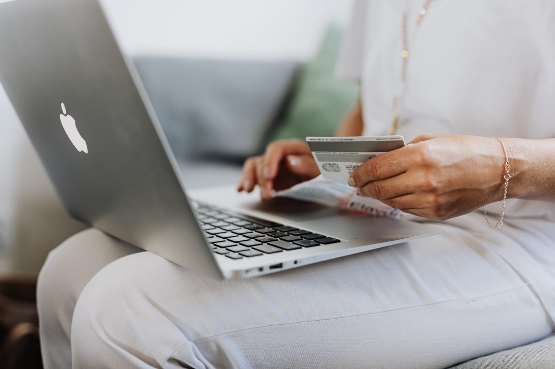 A woman with her laptop open on her laptop and her credit card on her hand