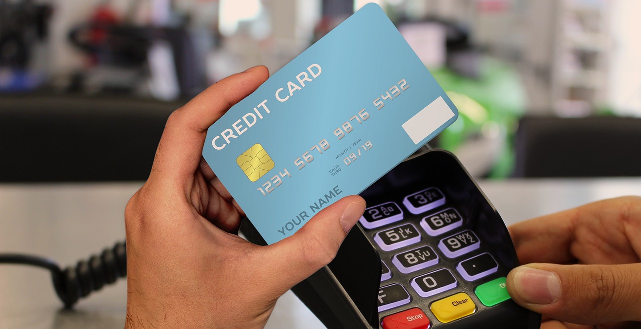 A man holding a blue credit card and a payment terminal