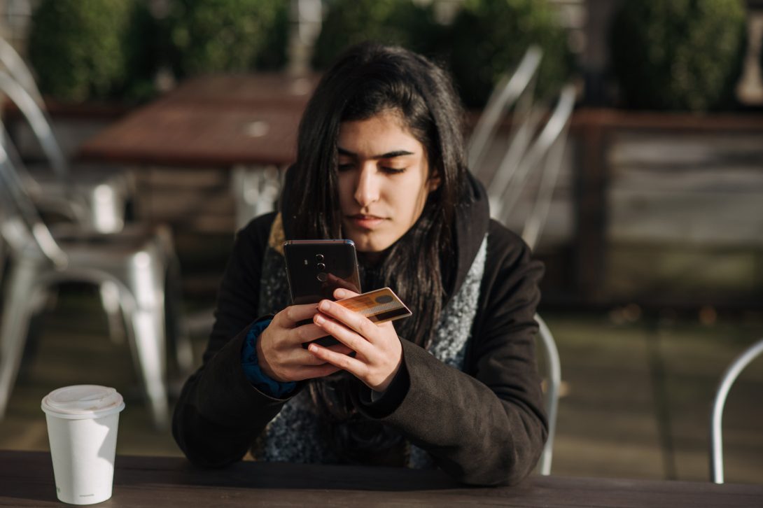 A woman using her phone while holding her credit card