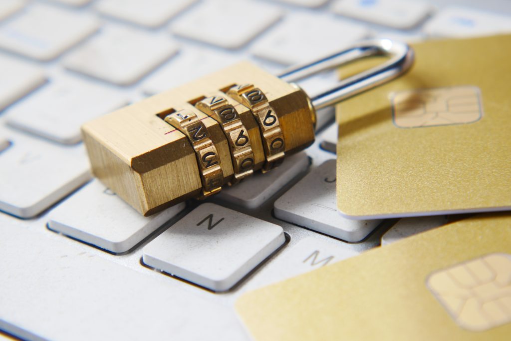 A lock and two gold credit cards on top of the laptop's keyboard