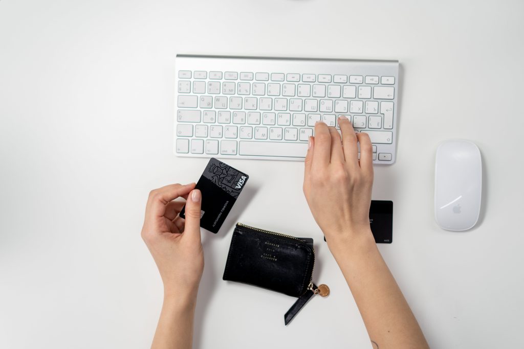 A woman typing on her keyboard while holding a black credit card
