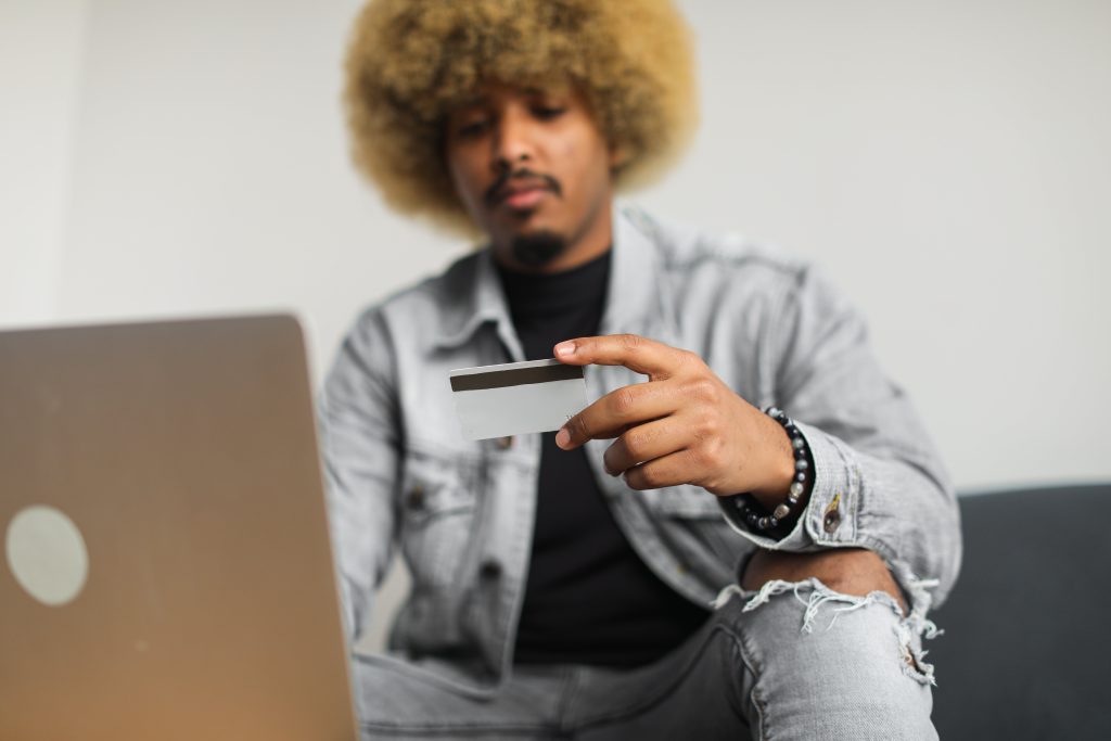 A man looking at her credit card with his laptop open in front of him