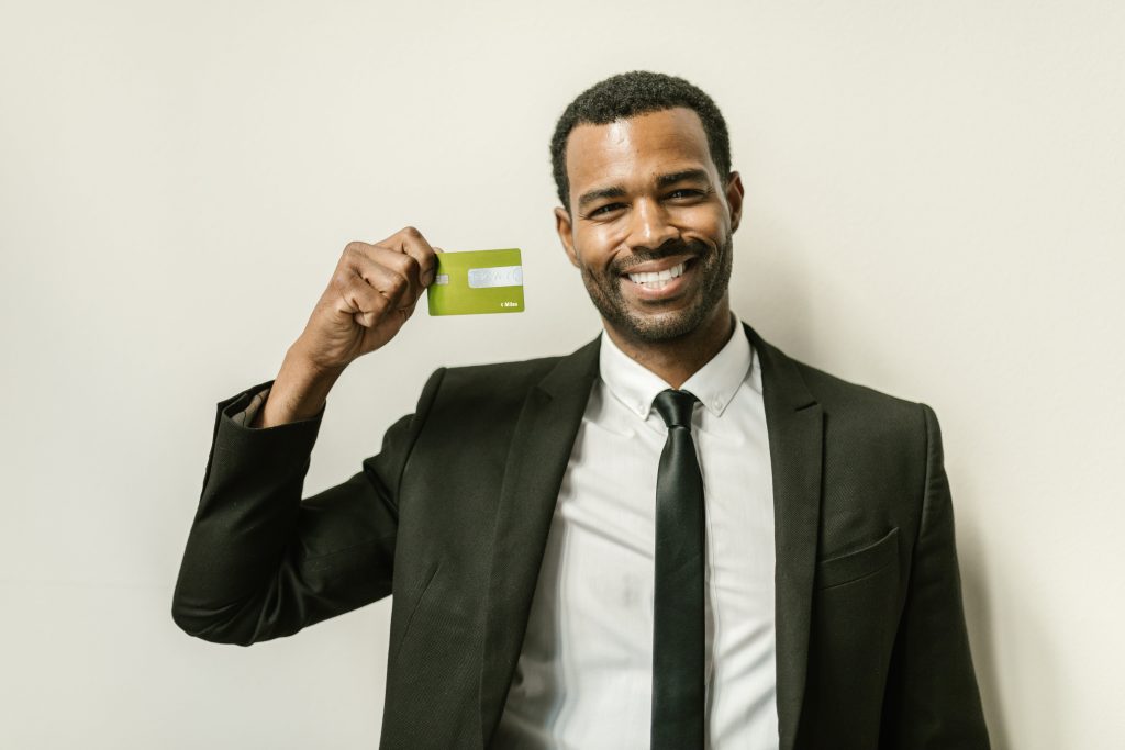A man wearing a formal suit smiling while holding his credit card