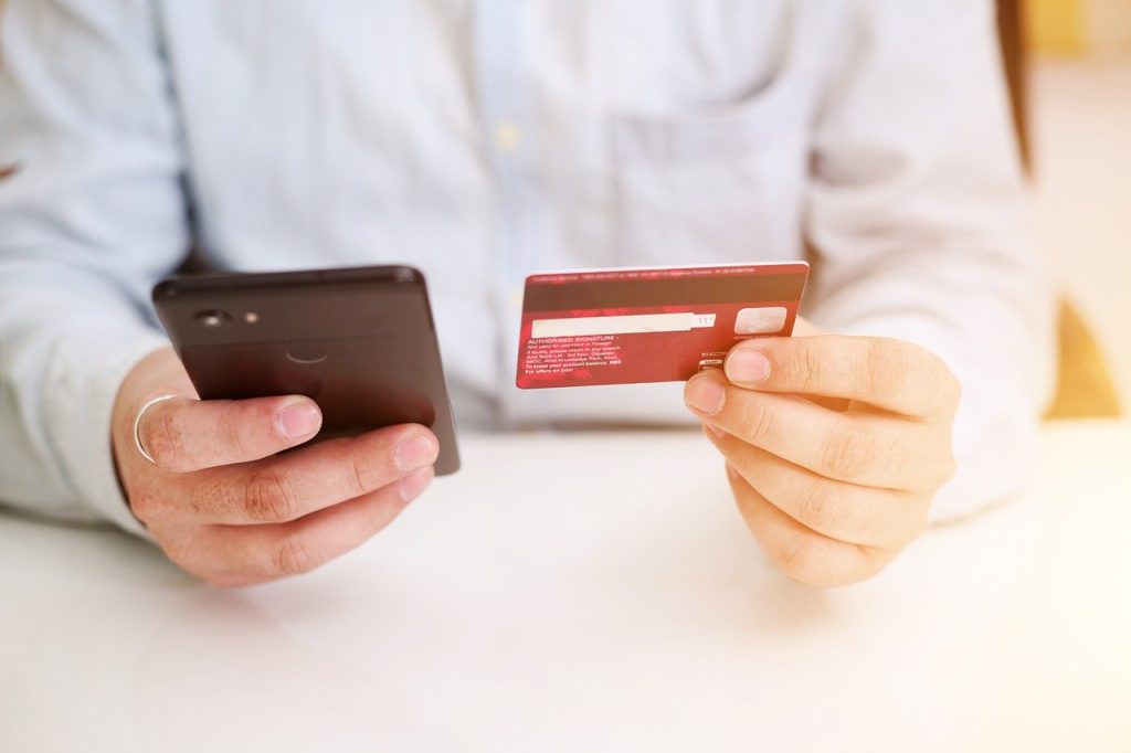 A man holding a phone and a credit card