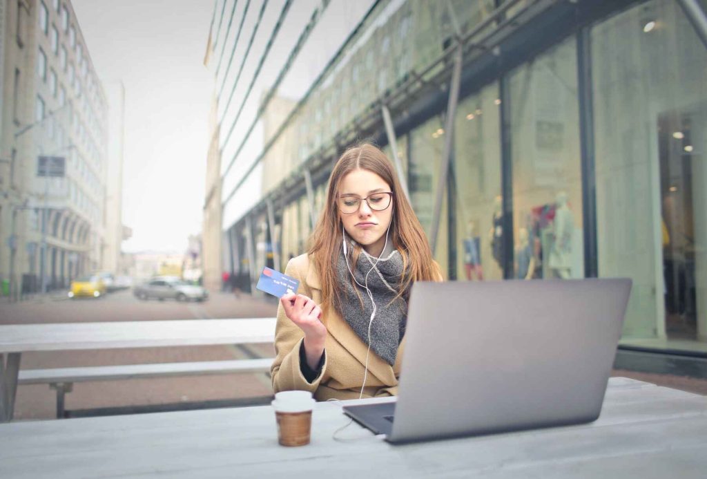 Woman holding a credit card with her laptop in front of her