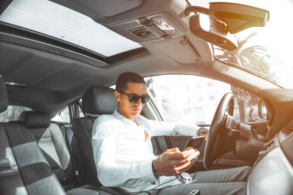 A man on a driver's seat using his phone