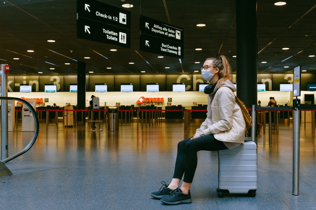A woman sitting on her luggage while waiting at the airport