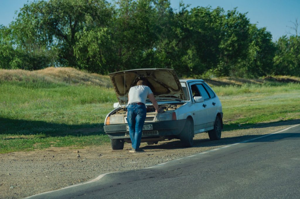 A man looking on the engine of his car with its hood open