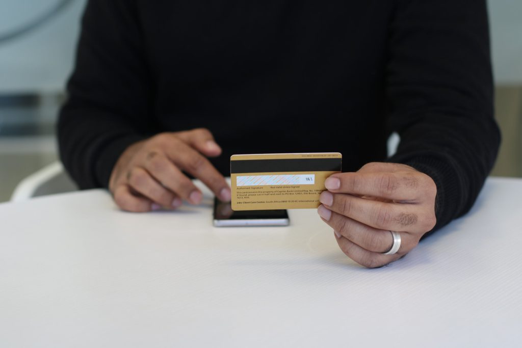 A man holding a credit card while tapping something on his phone