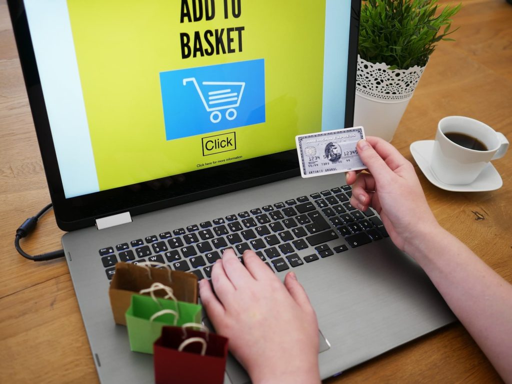 Person holding a credit card while adding new items on her online basket